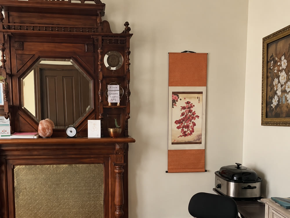 The room's original carved mantel and gold fireplace insert, beside the massage table