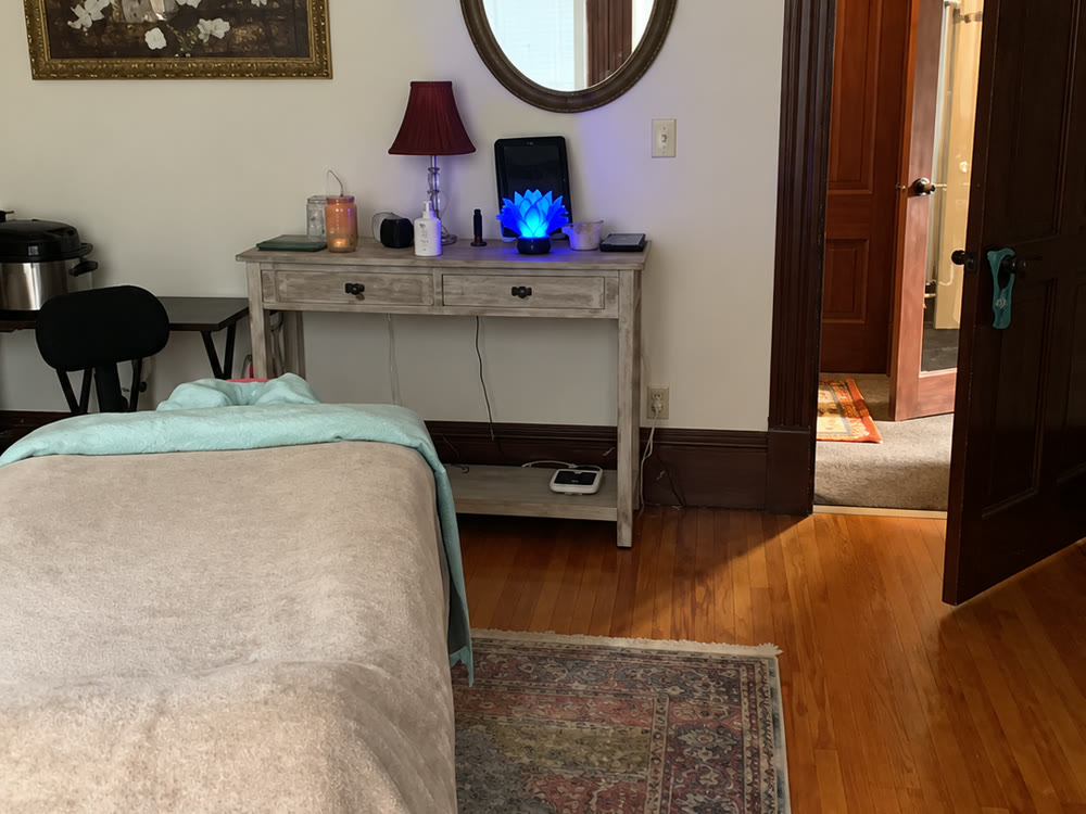 The treatment room: massage table made up in fresh linens, a console with candles and a mirror